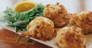 close up view of four golden brown crab cakes