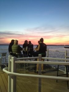people gathering on a deck watching the sunset over the bay