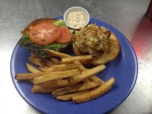 a crab cake on a burger roll with fries