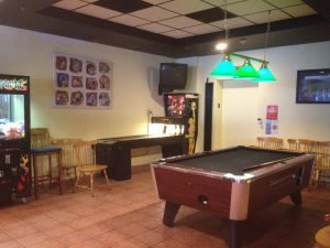 a room with a few arcade games and a pool table