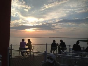 Four people sitting on a deck looking at the sunset